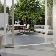 Nowoczesny taras z dużymi, szarymi płytkami, gdzie stół z krzesłami i sofa zapraszają do relaksu.