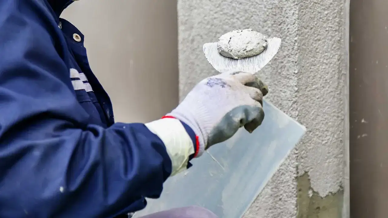 Pracownik w rękawicy nakłada tynk na ścianę. Zastanawiasz się, ile kosztuje metr tynku?